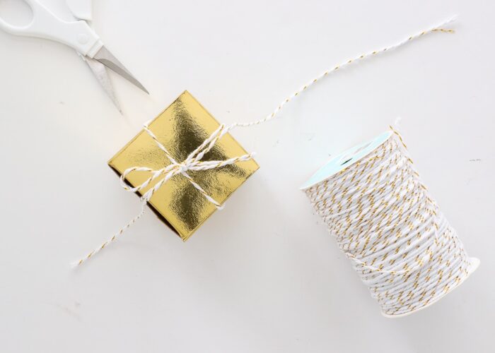 3D box cut from gold foil Kraft board wrapped with white string.