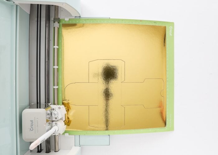 Cricut Explore Air 2 shown with gold foil Kraft board on a Standard Grip Mat.