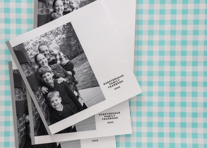 Black-and-white Family Yearbooks stacked on a turquoise plaid background.