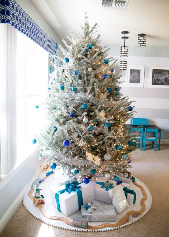 White flocked tree with blue, silver, and turquoise Christmas ornaments.