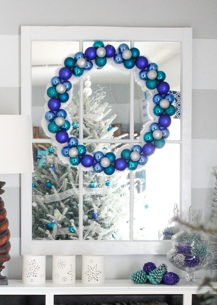 Blue, white and turquoise Christmas ornaments wreath above bookcase.