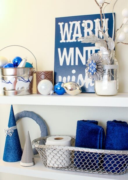 Blue and white Christmas decor on white bathroom shelves.
