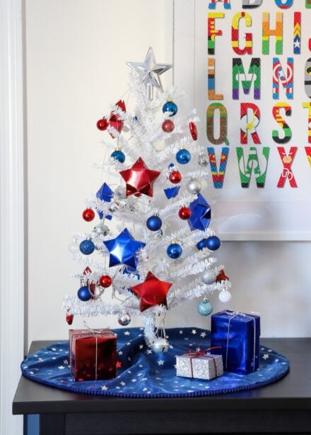 Navy blue mini tree skirt on a small white tree with red, white, and blue ornaments.
