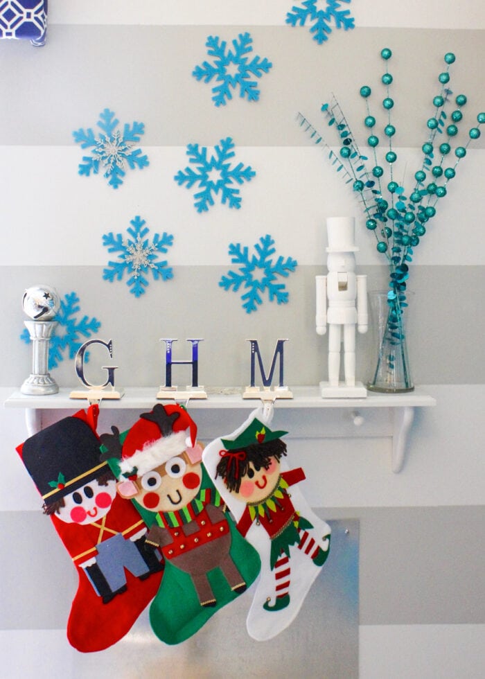 Blue felt snowflakes on wall above Christmas stockings