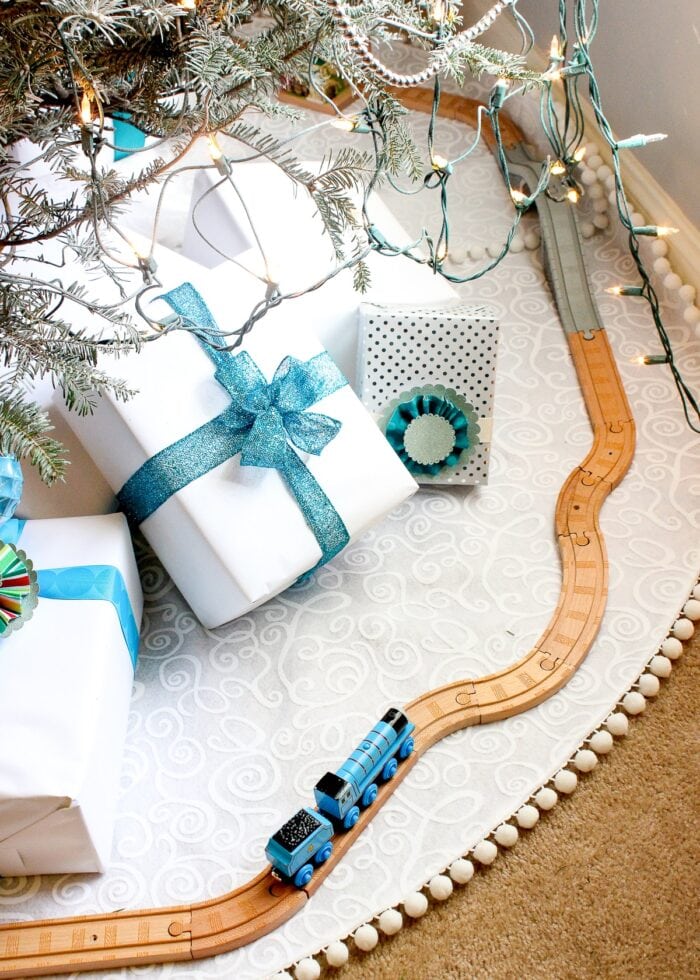 White Christmas tree skirt with white and turquoise presents.