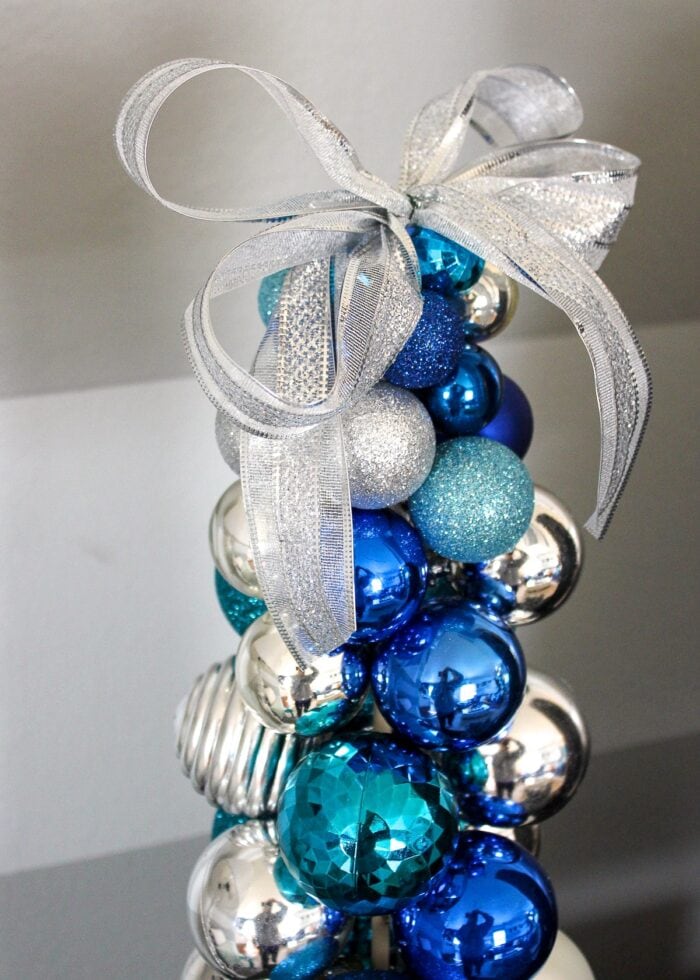 Blue, silver, and turquoise ornament tree with silver bow on top.