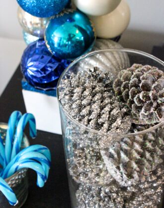 Silver glittered pinecones in a glass vase.