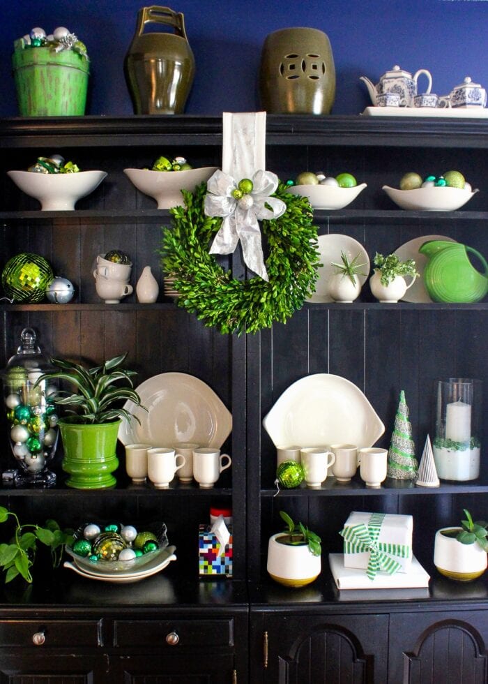 Black bookcases filled with green Christmas decorations.