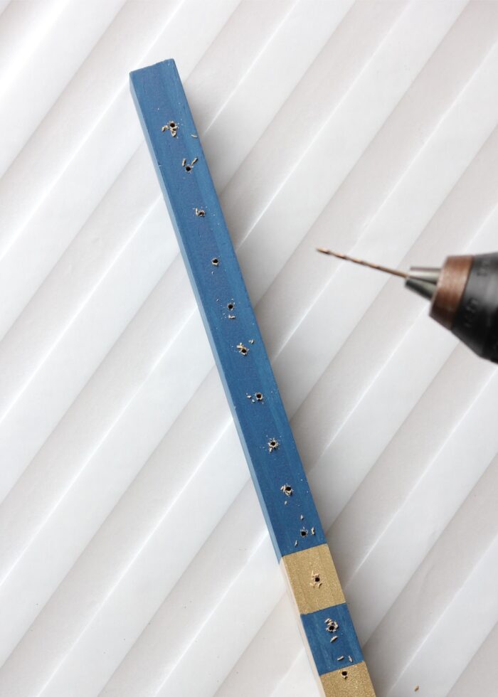 Blue wooden dowel with holes drilled into it.
