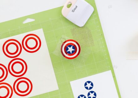 Cricut mat shown with red, white, and blue vinyl designs being layered onto a wooden knob
