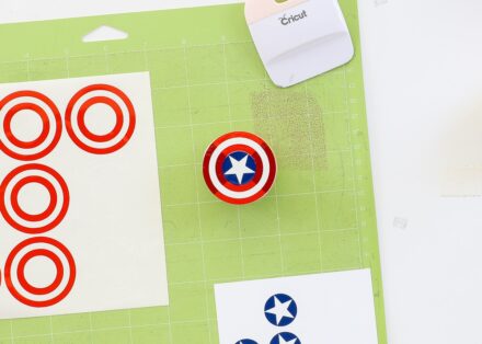 Cricut mat shown with red, white, and blue vinyl designs being layered onto a wooden knob