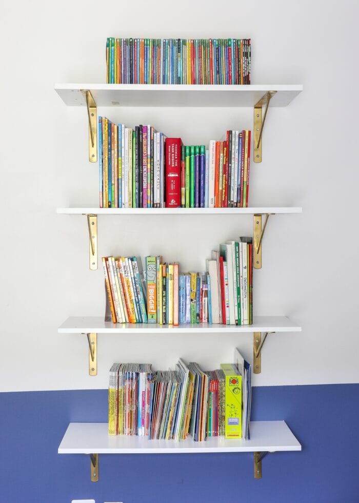 Floating bookcase on a white wall loaded with books