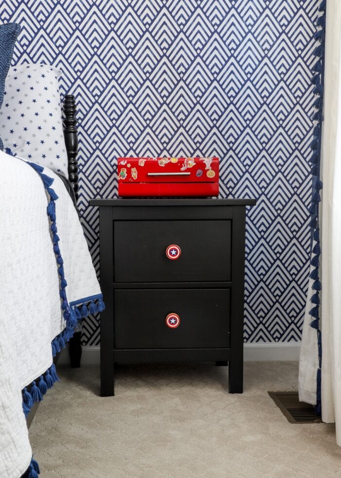 Black nightstand against a navy blue and white wallpapered wall