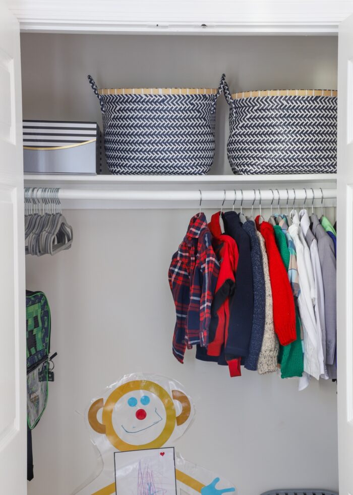 Kids closet with clothes on hangers and baskets on shelf