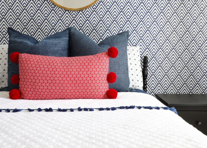 Blue and white wallpaper behind a black bed with red, white, and blue linens