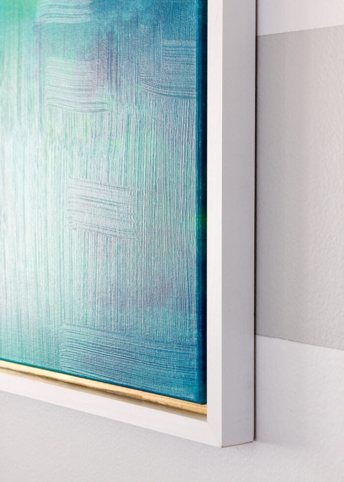 Edge of framed canvas on a striped wall