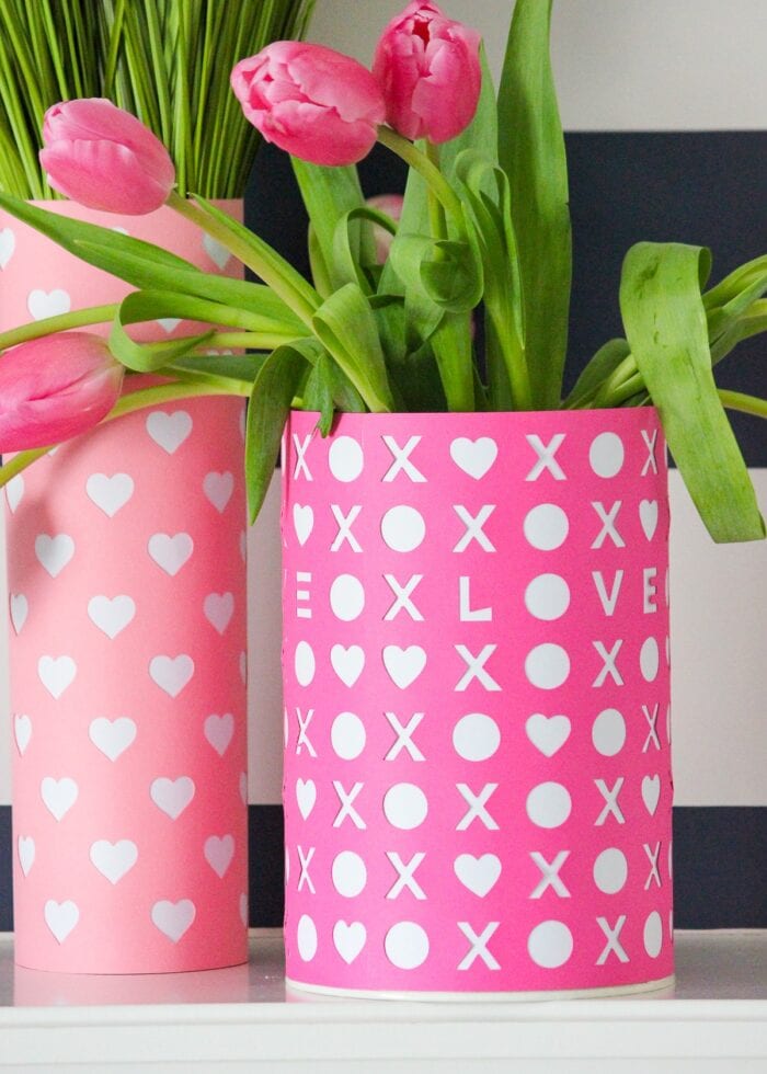Pink Valentine's Day vases with tulips against a striped background