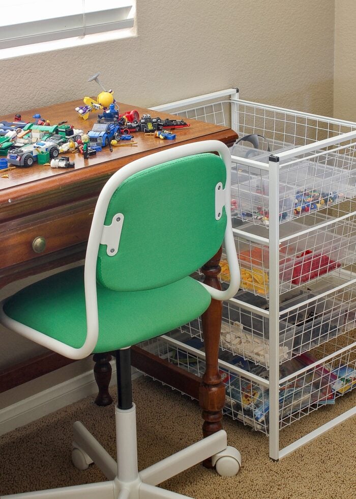 LEGO brick storage drawers next to a wooden desk with green chair