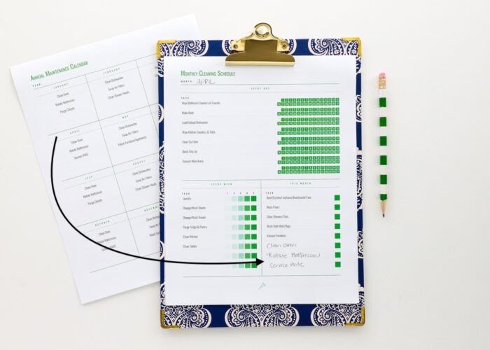 Blue clipboard holding home cleaning schedule printables from The Family HUB
