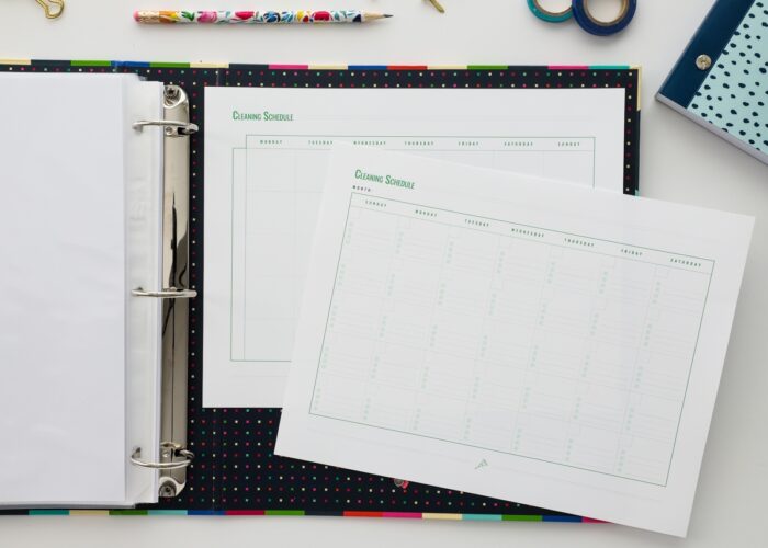 Binder open showing home cleaning schedule printables from The Family HUB