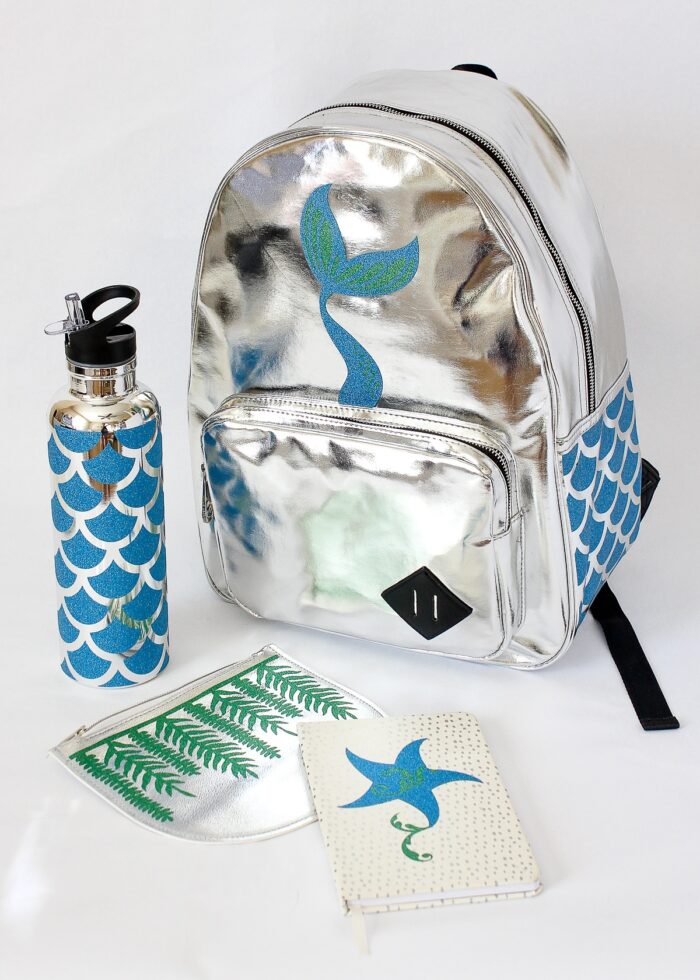 Mermaid scales made of glitter vinyl on a silver backpack, water bottle, and accessories
