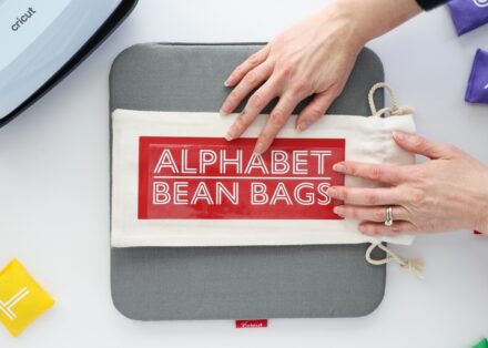 Hands placing a layer of words onto Cricut Wine Bag