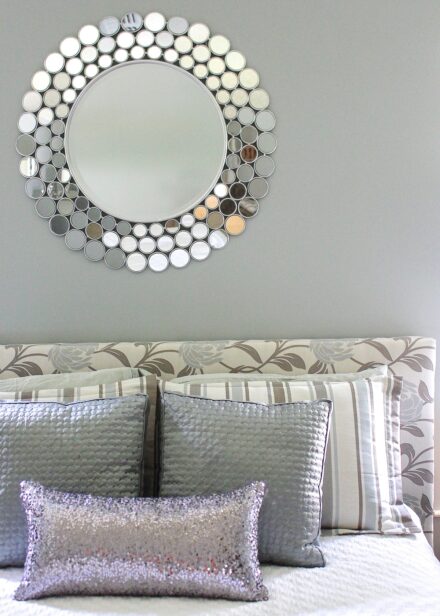 Silver spray painted mirror hung above bed