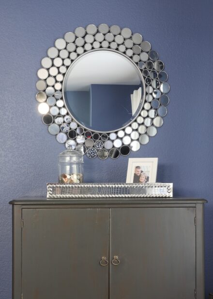 Silver spray painted mirror hung above a dresser