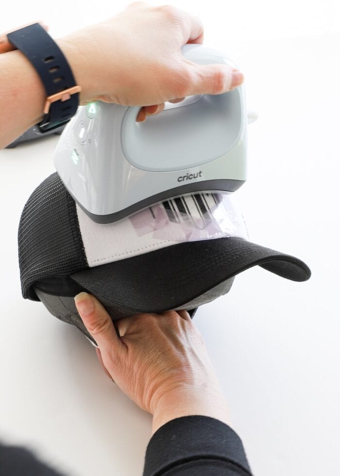 Hand holding Cricut Hat Press on a Cricut Trucker Hat