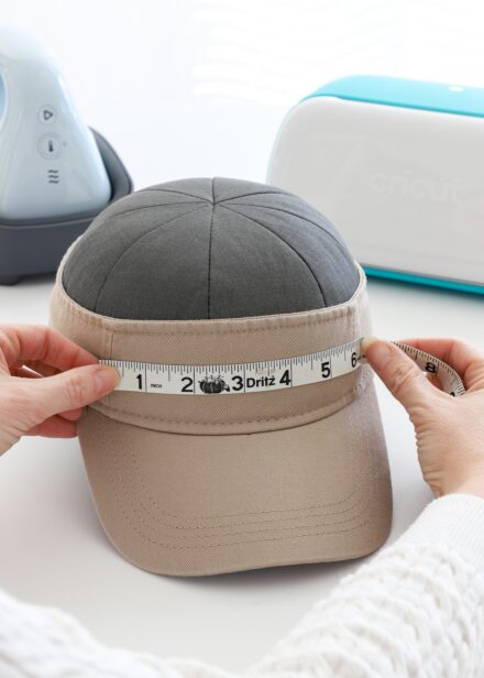 Hands measuring the front of a tan visor with measuring tape