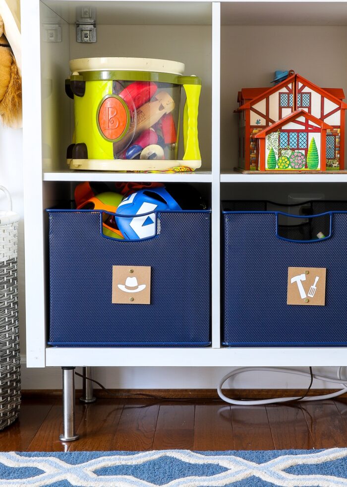 Navy blue baskets with cardboard labels on playroom shelves