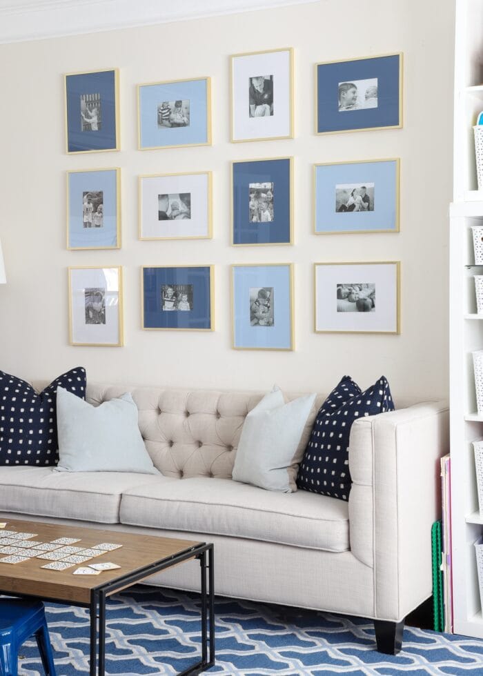 Beige tufted couch with blue gallery frames hung on wall above