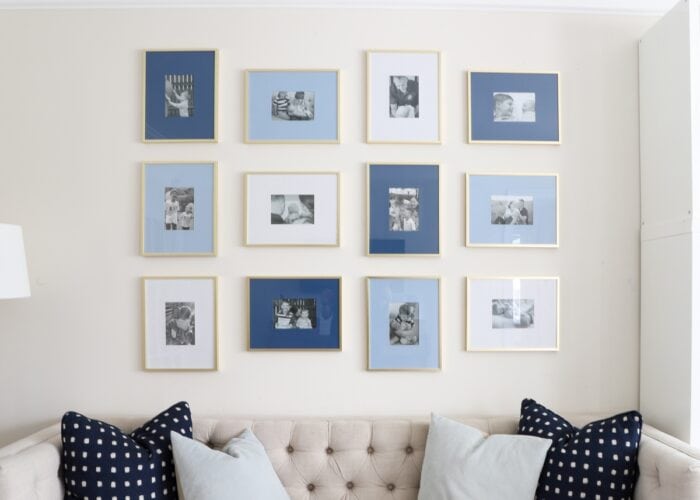 Beige tufted couch with blue gallery frames hung on wall above