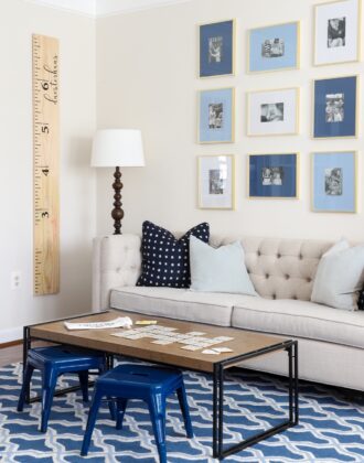 Brown coffee table in a playroom on a blue rug with wall ruler and couch