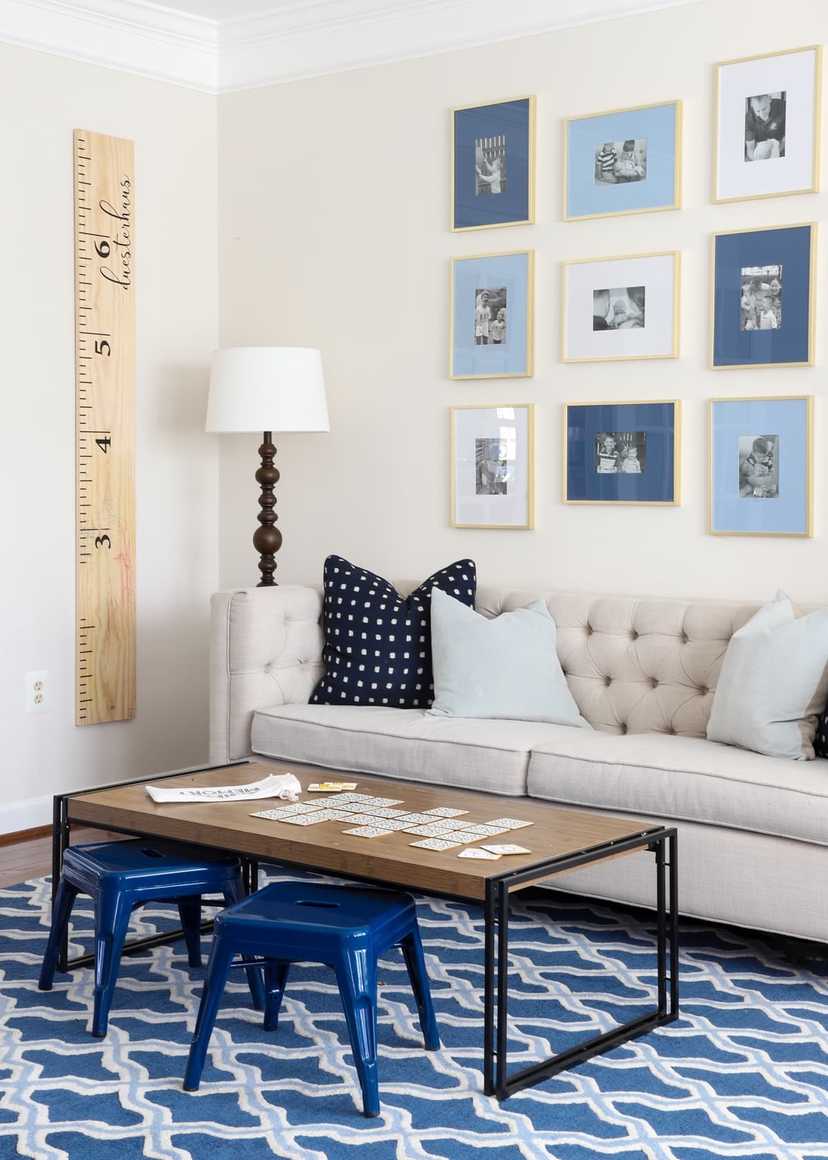 Brown coffee table in a playroom on a blue rug with wall ruler and couch