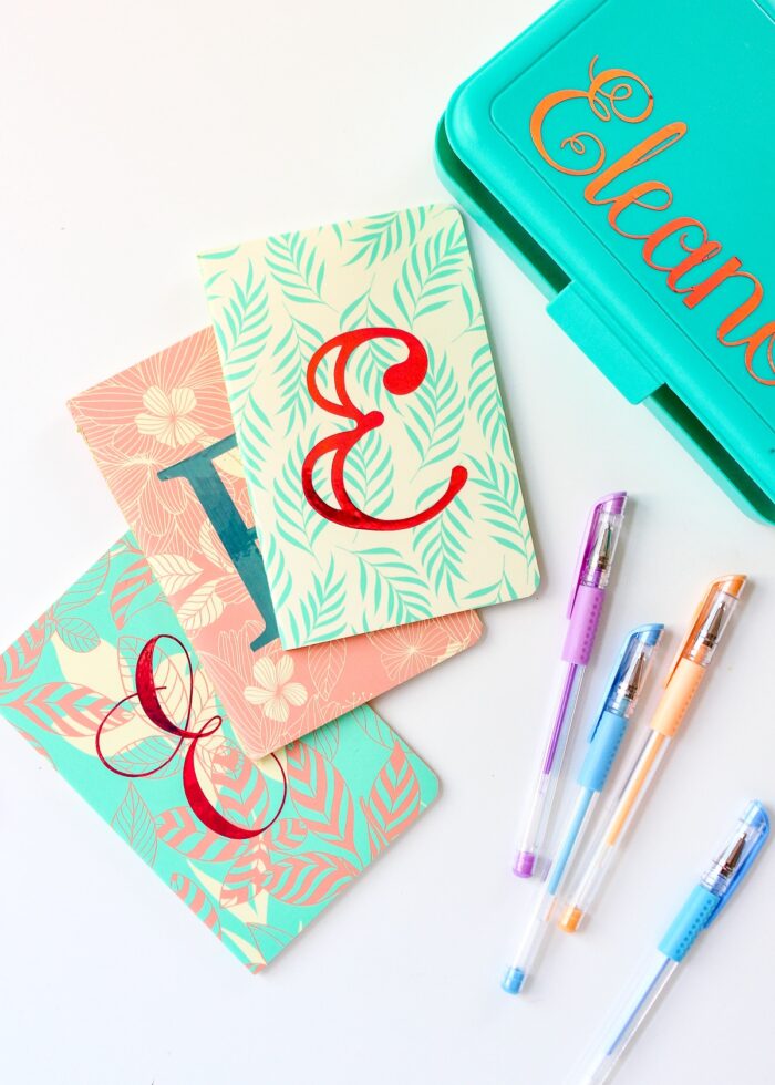Monograms cut from Adhesive Foil and Cricut Holographic Vinyl on the front of small notebooks