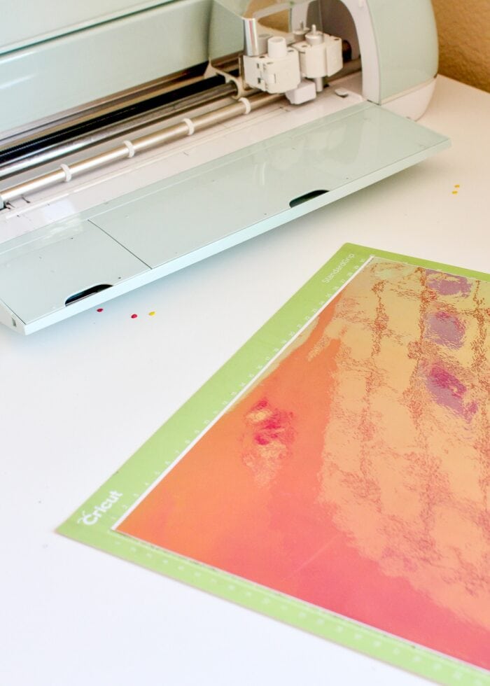 Holographic Vinyl on a green cut mat in front of Cricut Explore Air 2 machine