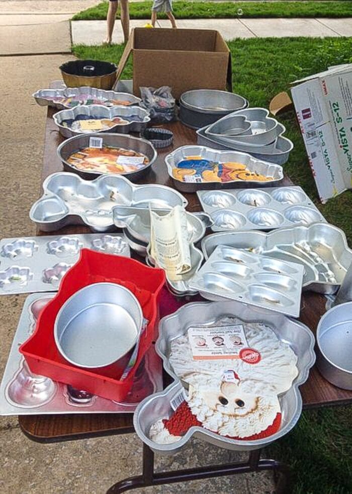 A yard sale table filled with cake pans