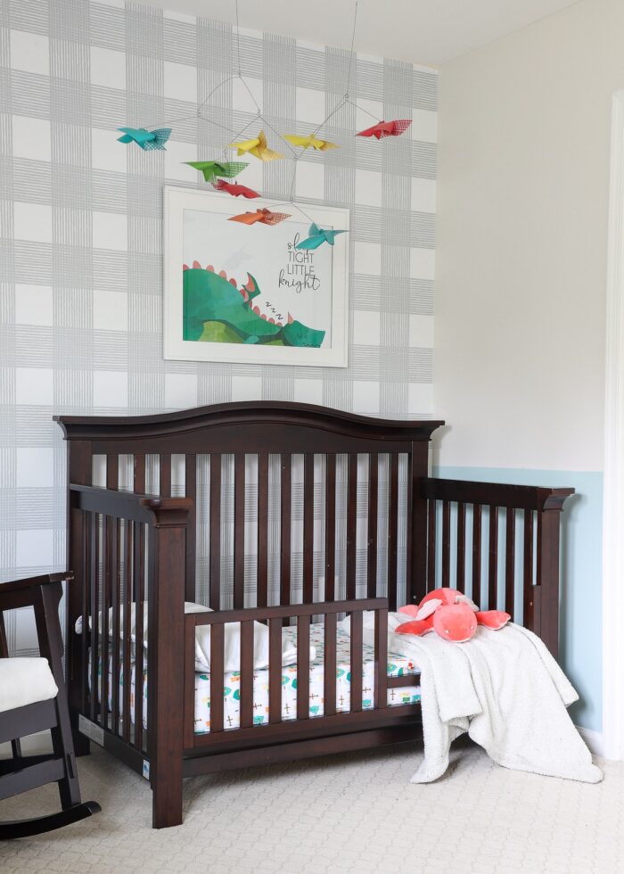 Dark crib in the corner of a Knight-themed nursery with mobile overhead