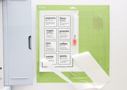 Printable pantry labels shown on a green cut mat with the excess sticker paper being pulled away