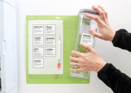 Hands placing a pantry label onto a clear jar