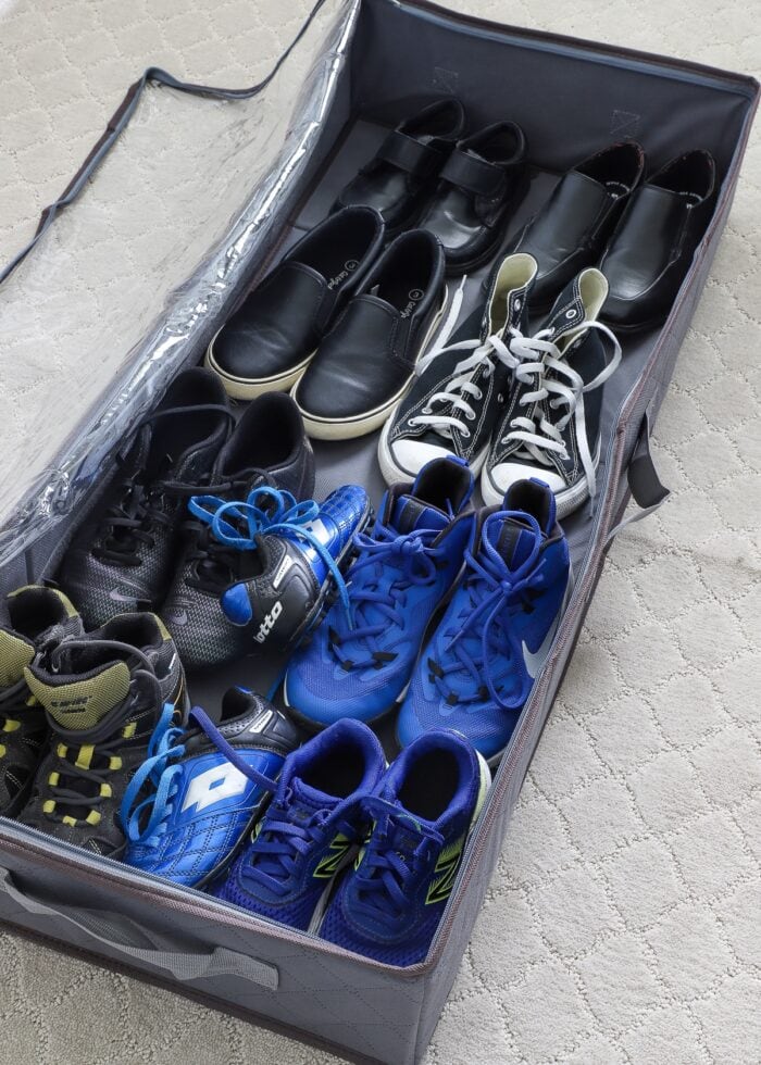 Kids shoes stored in an under-bed storage tote.
