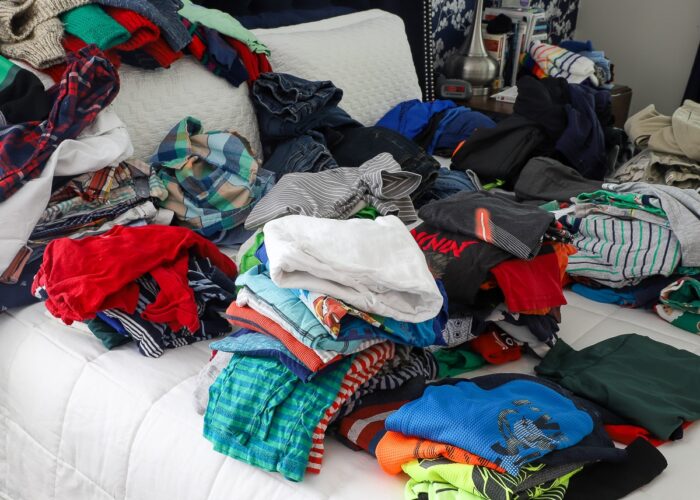 Piles of kids clothes on a bed