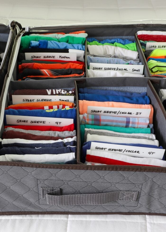 Storing baby clothes vertically in under-bed storage totes.