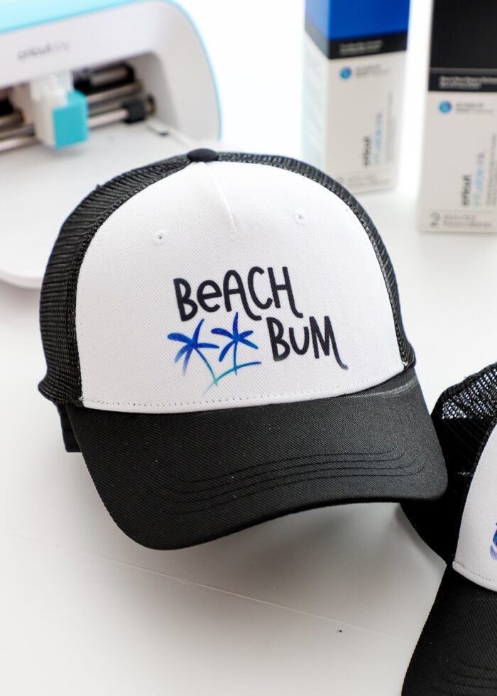 A black trucker hat that says "Beach Bum" in Cricut Infusible Ink