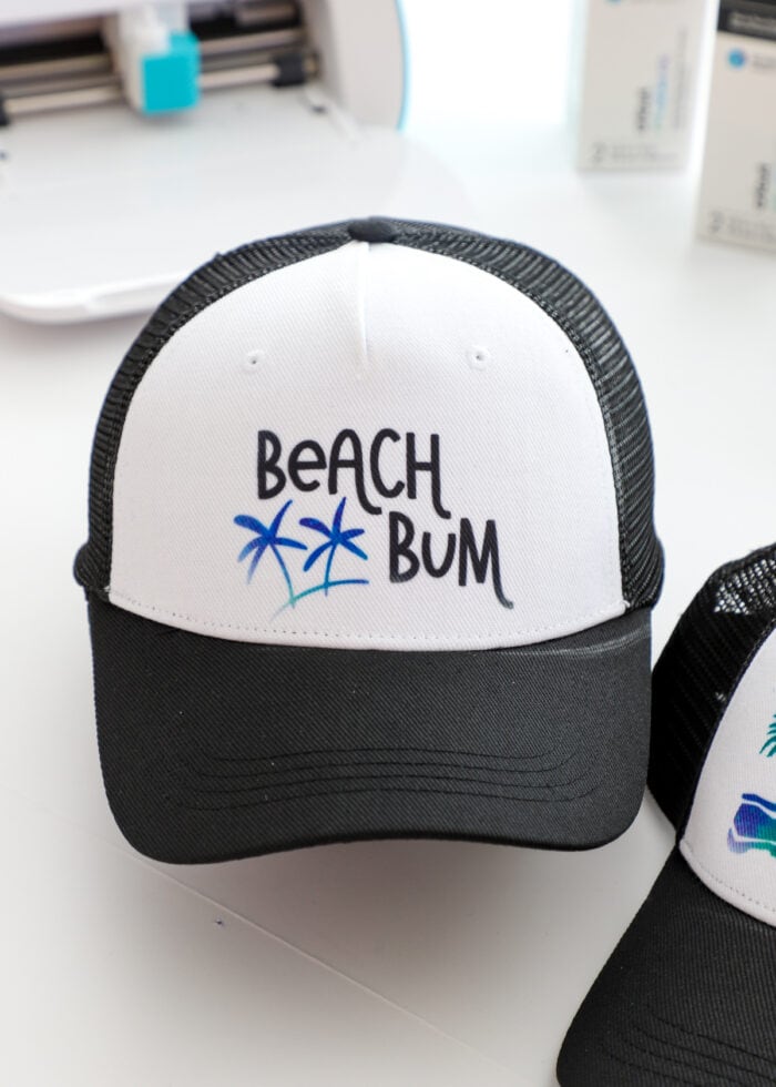 A black trucker hat that says "Beach Bum" in Cricut Infusible Ink