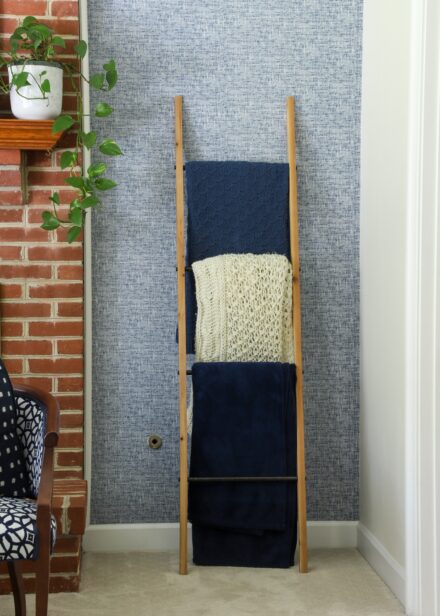 Blanket ladder leaning against a blue wallpapered wall