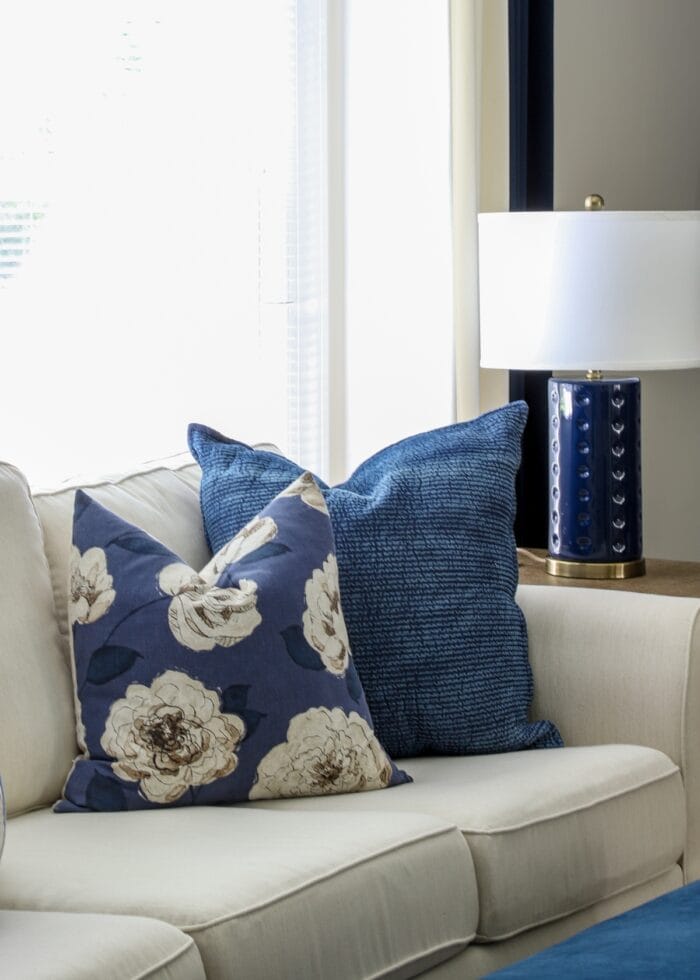 Navy blue pillows on a white couch next to a navy lamp
