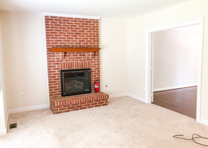 Empty family room with beige walls and red brick fireplace