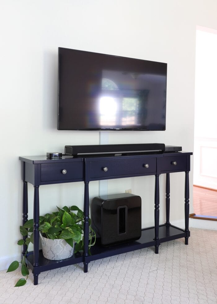 Navy blue console table underneath a wall-mounted television.